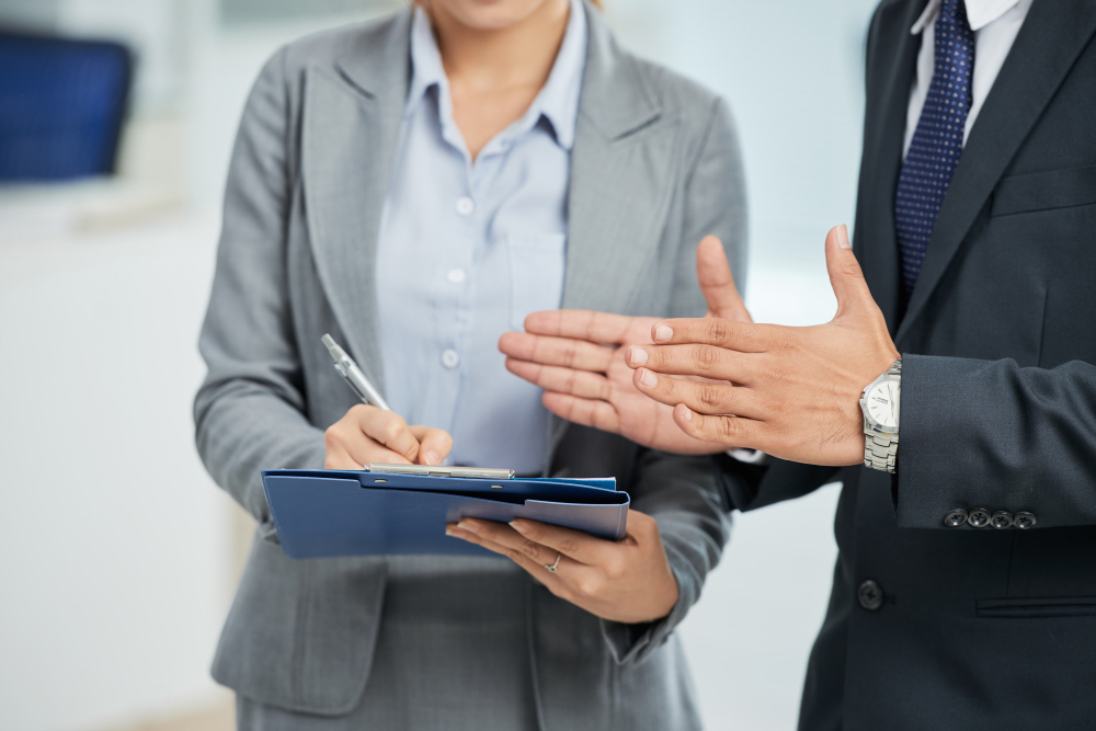 unrecognizable-man-suit-gesturing-woman-taking-notes