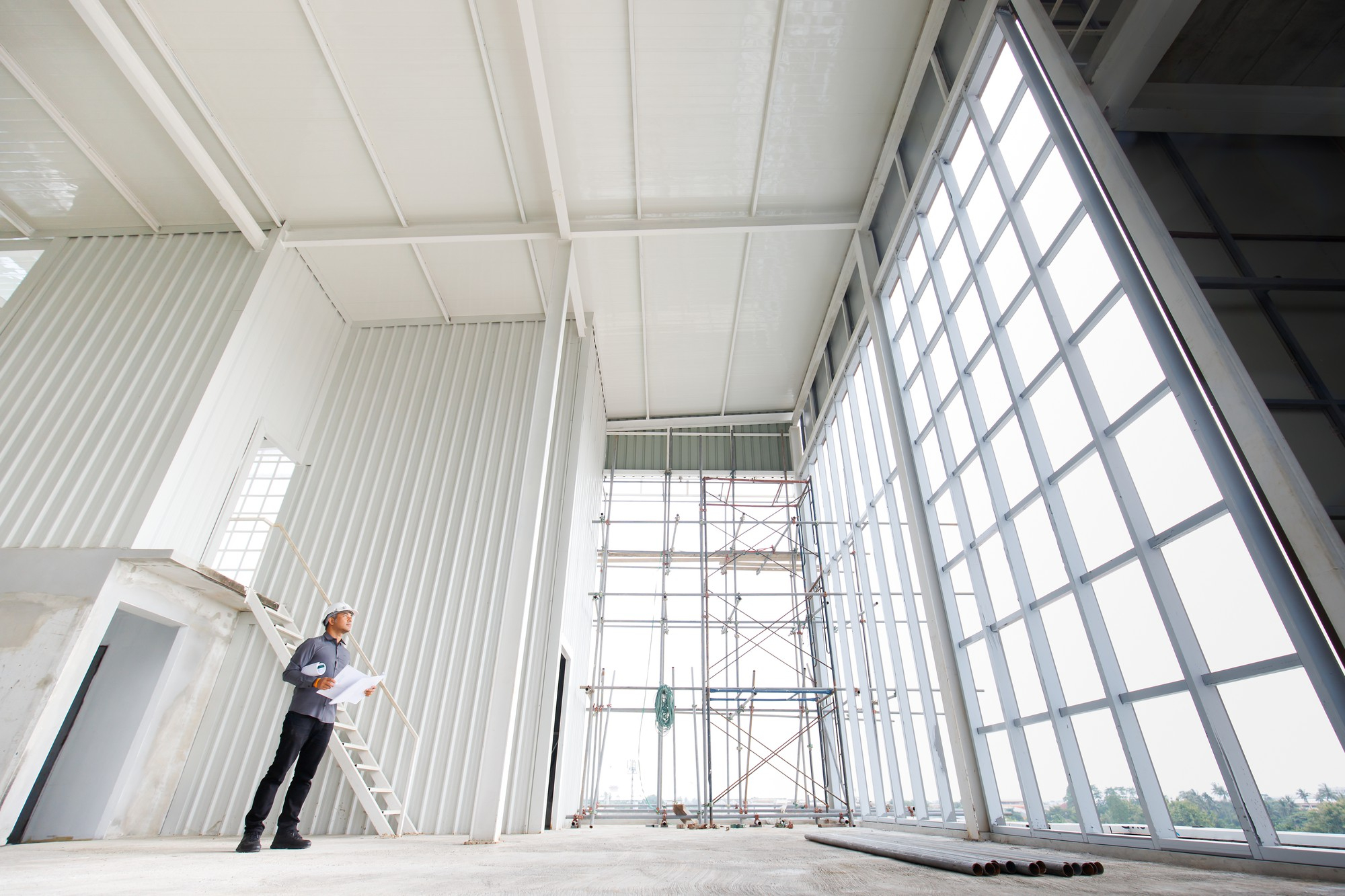 white-helmet-male-engineer-with-blue-print-is-checking-structure-underconstruction-building